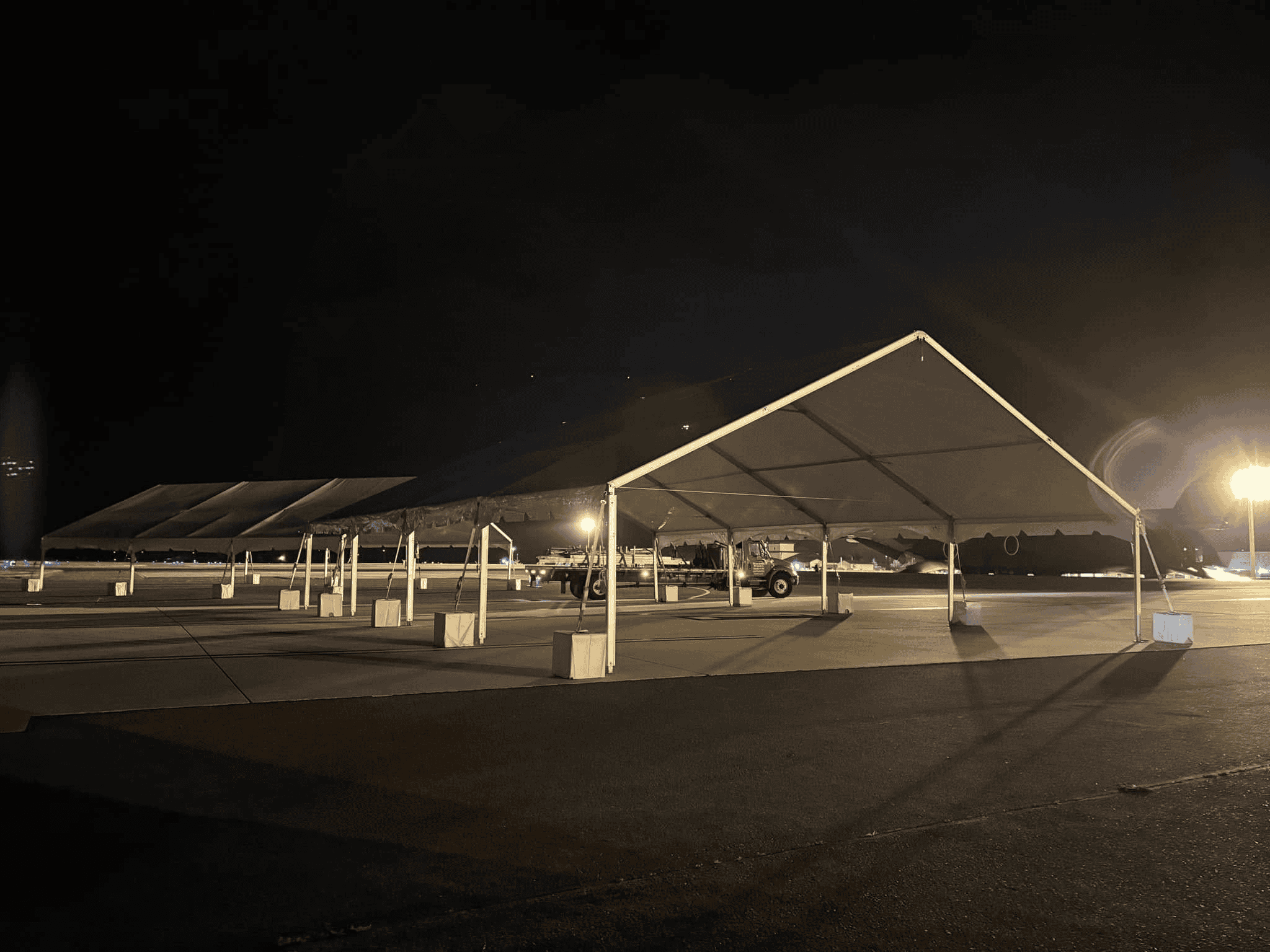 Ballasted tent legs on asphalt with cable runs managed along the edge
