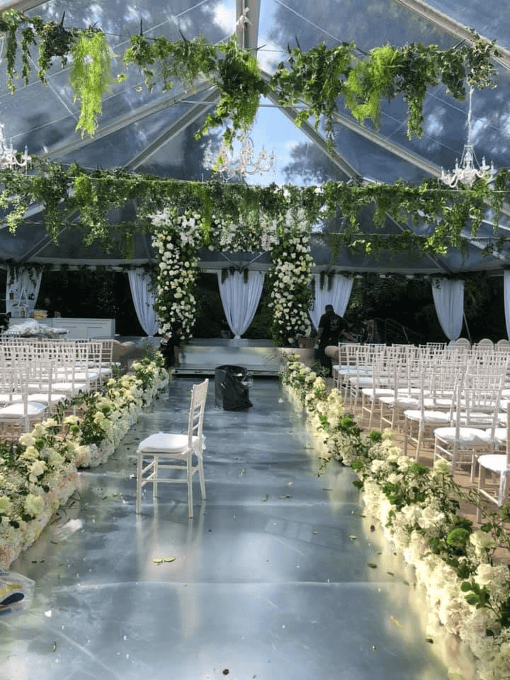 Mirrored aisle lined with white florals leading to a draped ceremony arch