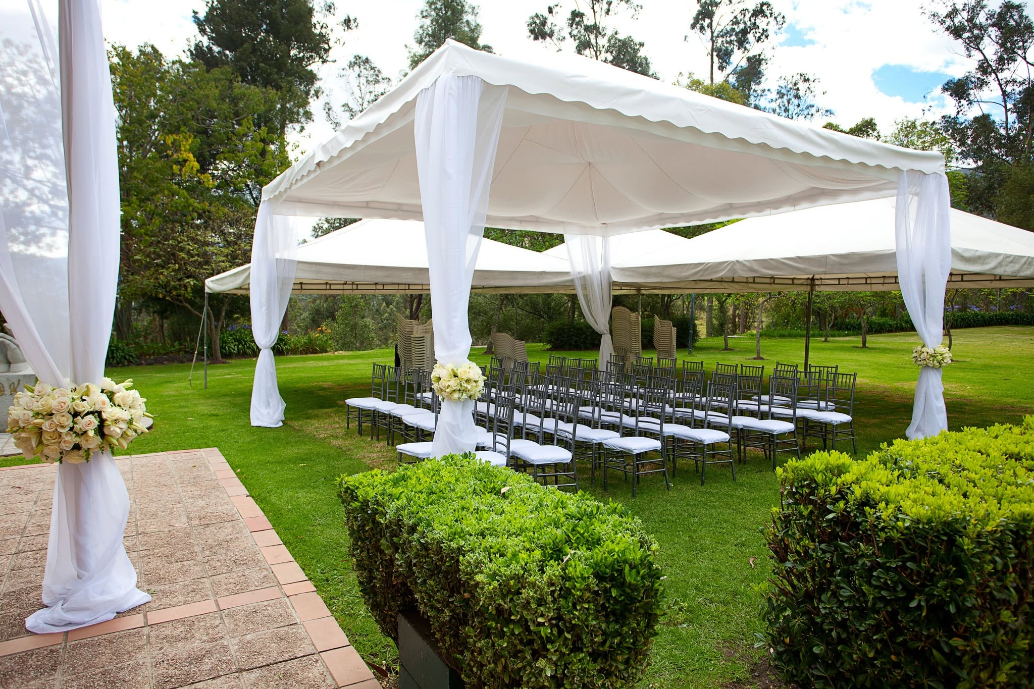 White draped canopy tent set over rows of ceremony chairs on a clipped lawn