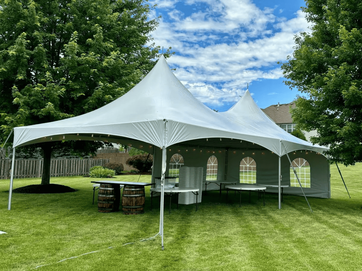 A high peak tent standing on a lawn under blue sky, installed by TGIF Event Services