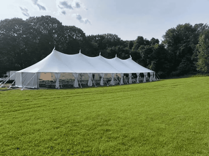 Sailcloth tent with a translucent top and wooden poles on a lawn