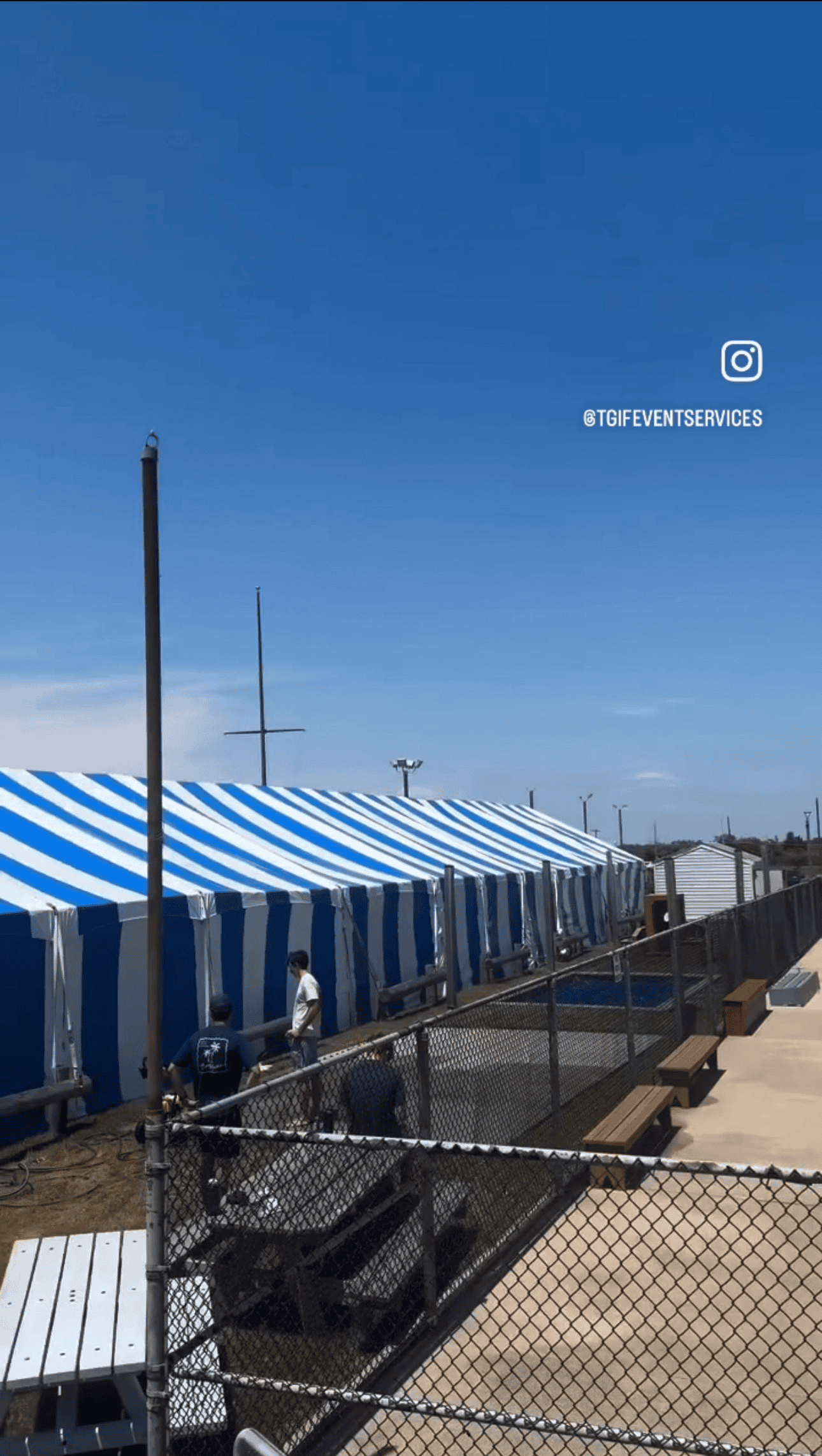 Wide tent frame under construction with sections laid out beside the footprint