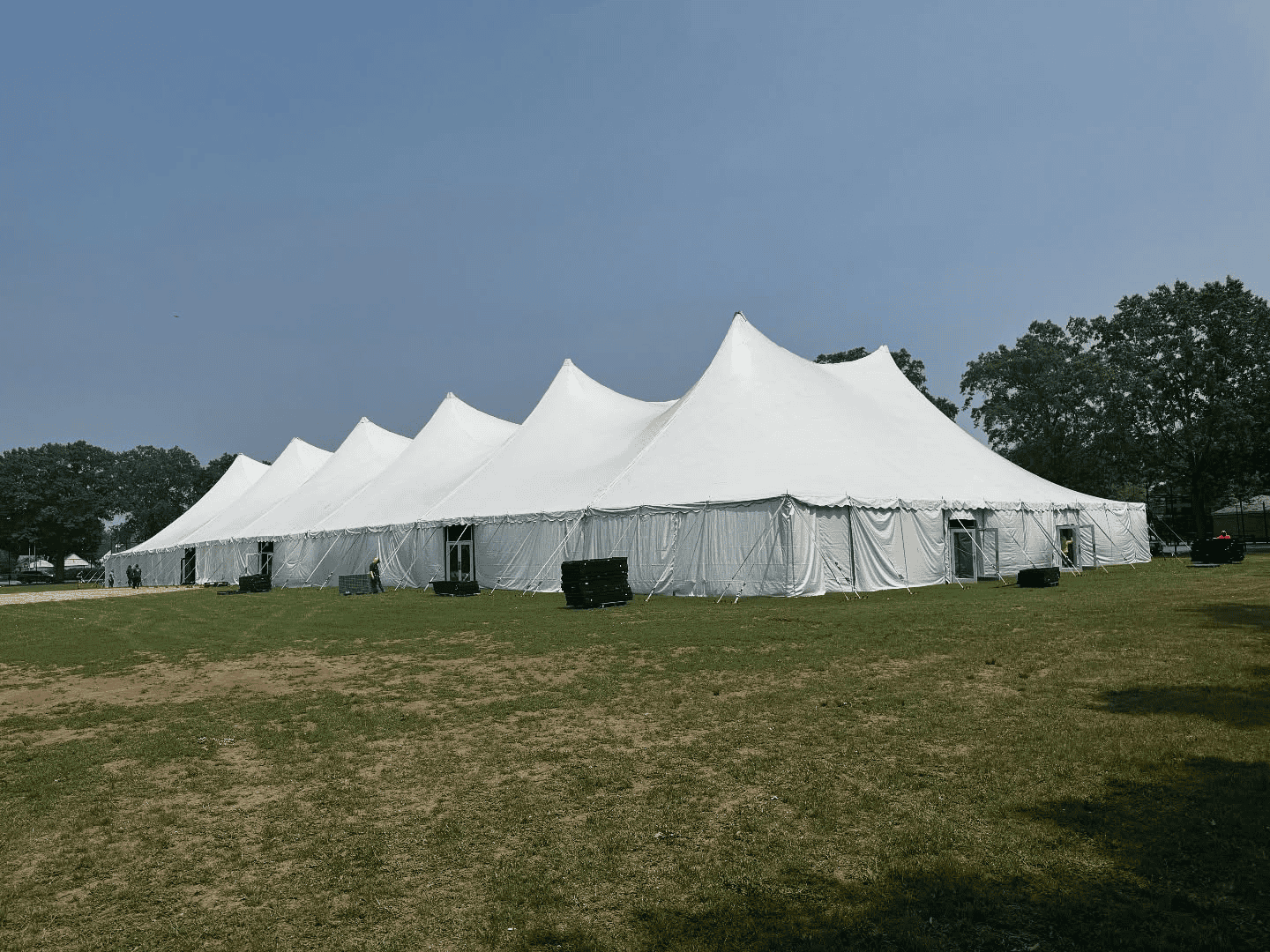 Rope and pole tent with center poles set up on an open lawn for an evening event