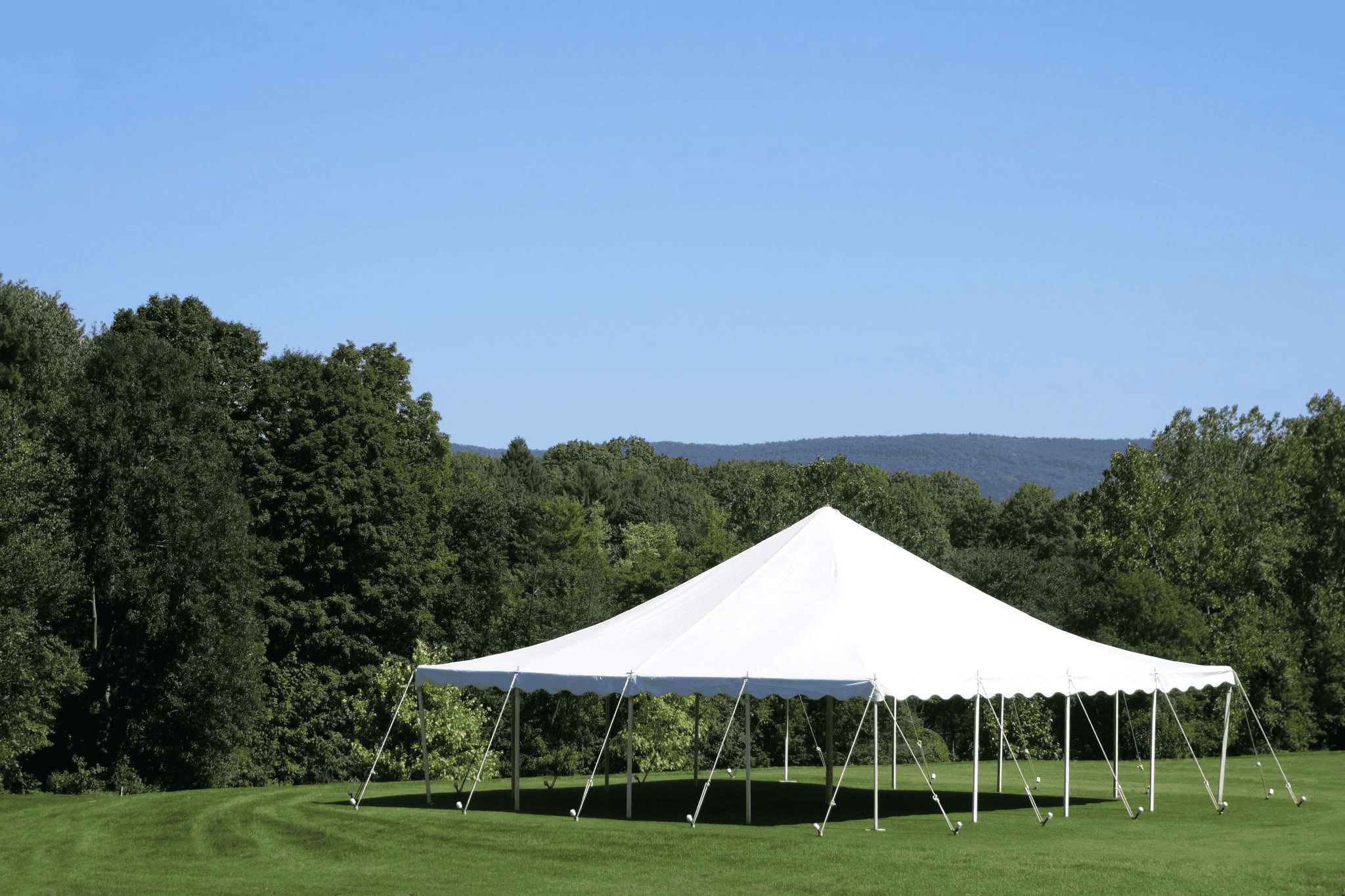 White rope and pole tent set for a seated dinner with round tables